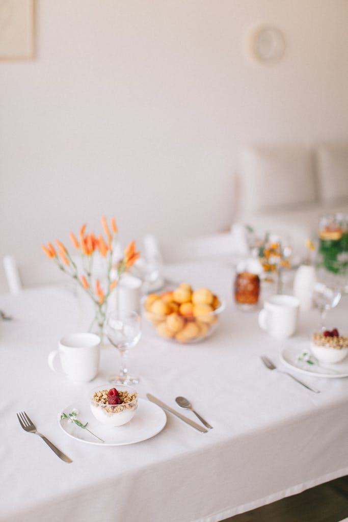 Beautifully set breakfast table with flowers and fruit, creating a serene dining ambiance.