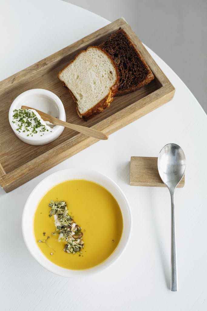 Delicious pumpkin soup served with fresh bread and a creamy dip, perfect for gourmet dining.