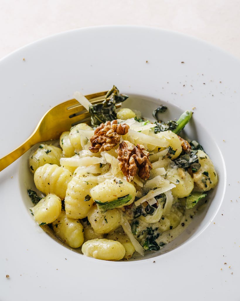 Elegant plate of gnocchi pasta topped with kale and walnuts, perfect for a gourmet meal.