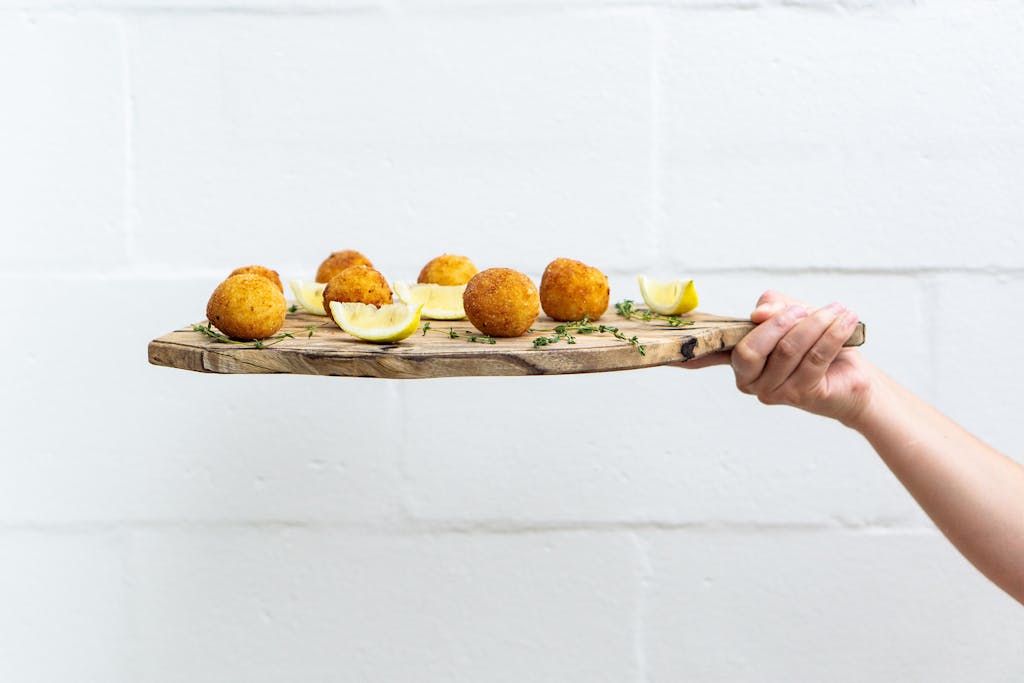 Tasty arancini balls served with lemon slices on a rustic wooden board, perfect for a fresh and healthy meal.