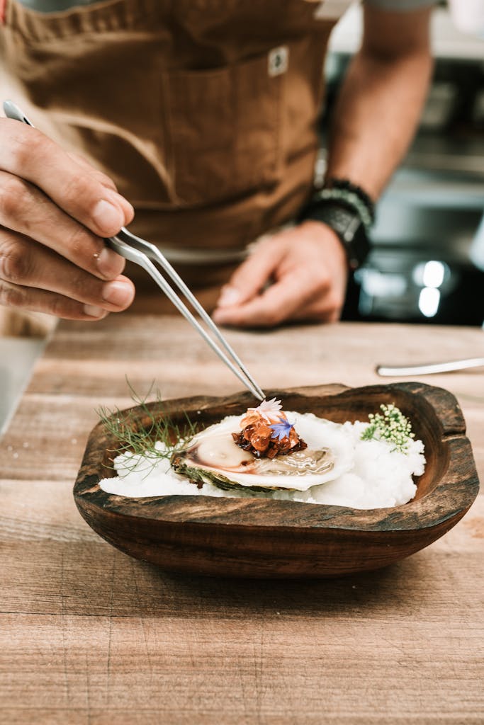 Chef delicately garnishing a gourmet oyster dish with culinary precision.