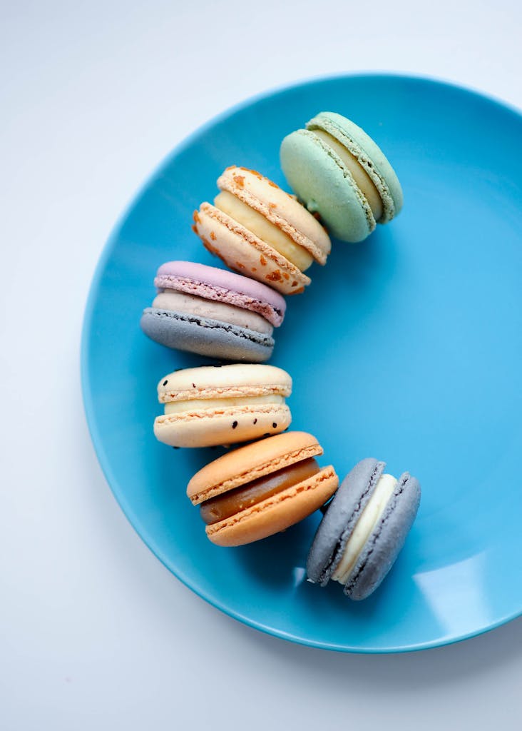 A vibrant assortment of macarons displayed on a vivid blue plate, showcasing their colorful variety.
